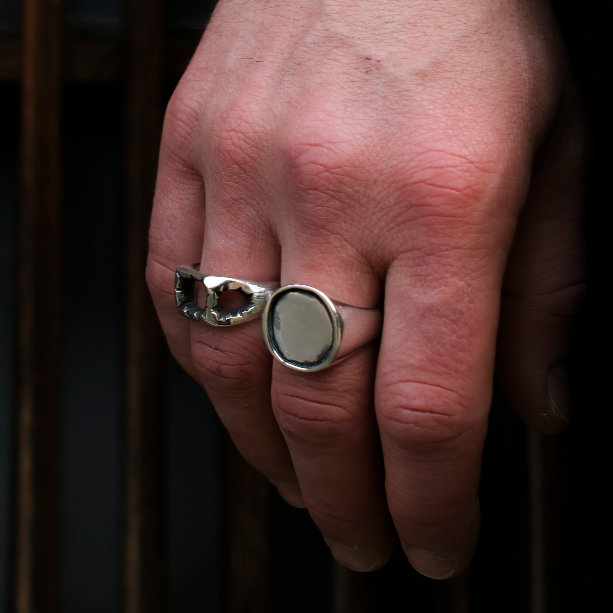 Hand wearing a silver ring with a dark background