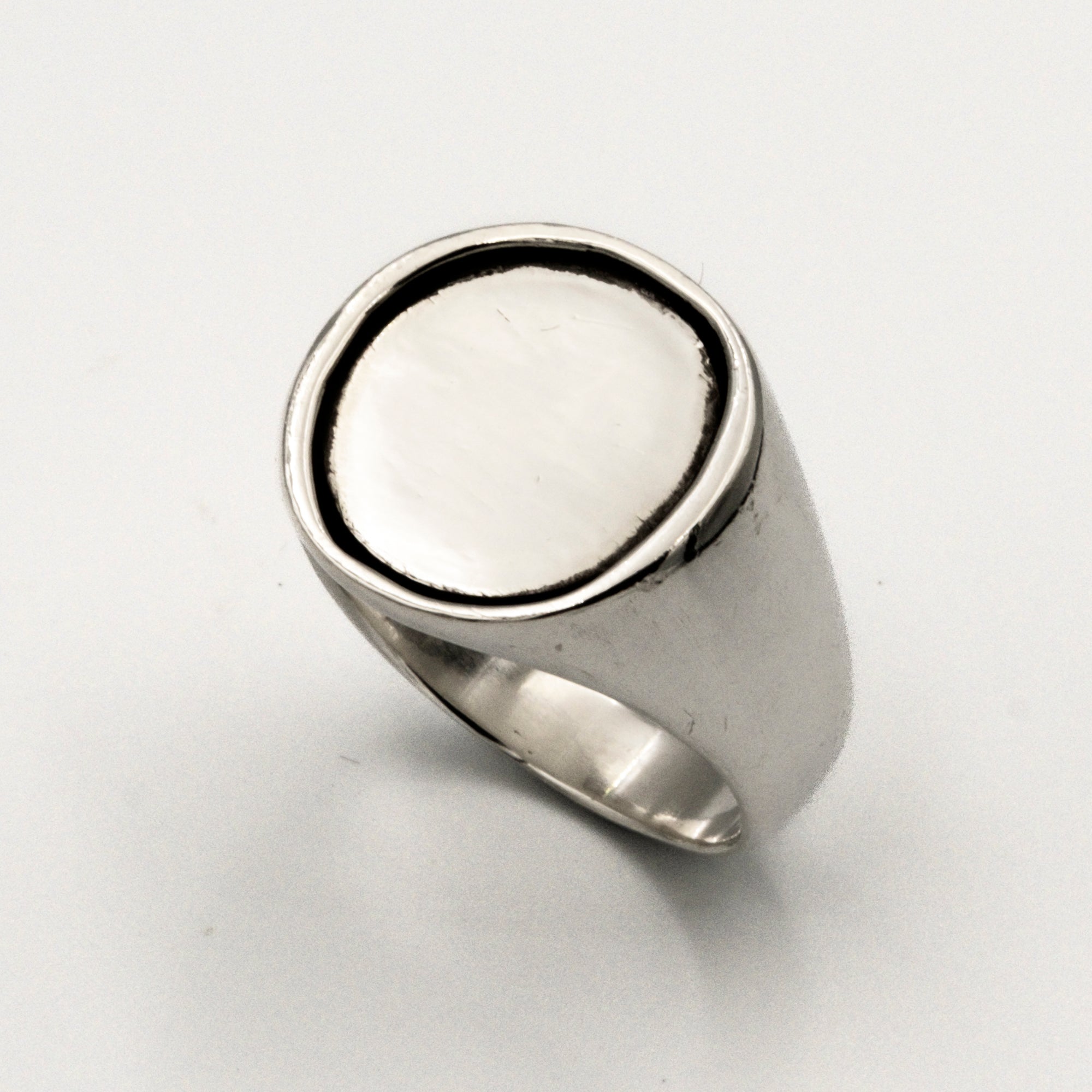 Silver ring with a silver coin inlay on a white background