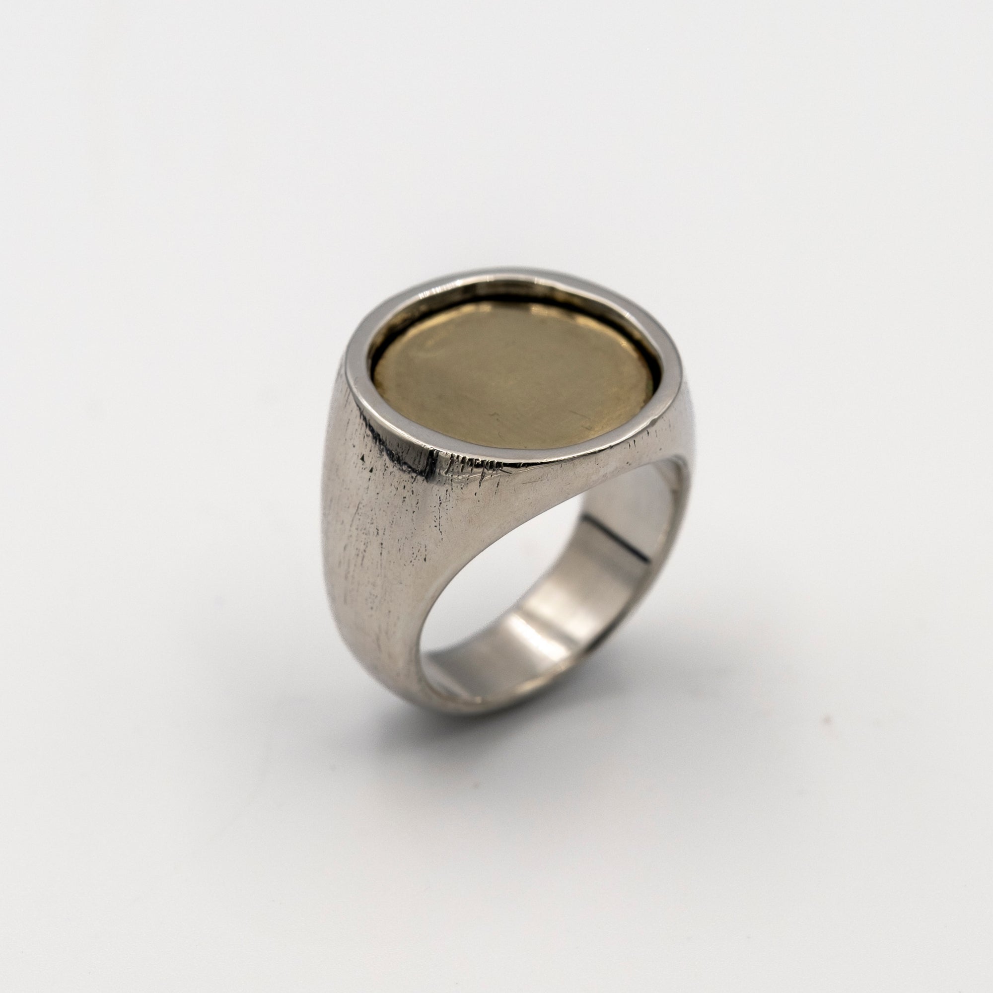 Silver ring with a gold coin inlay on a white background
