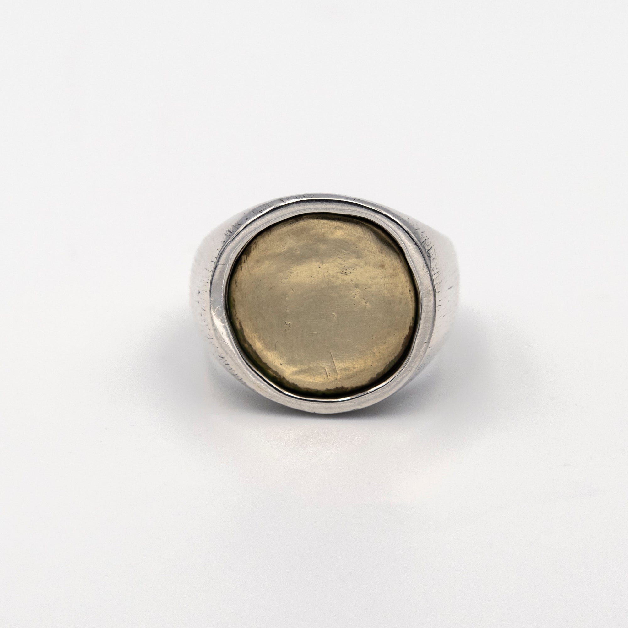 Silver ring with a gold coin inlay on a white background