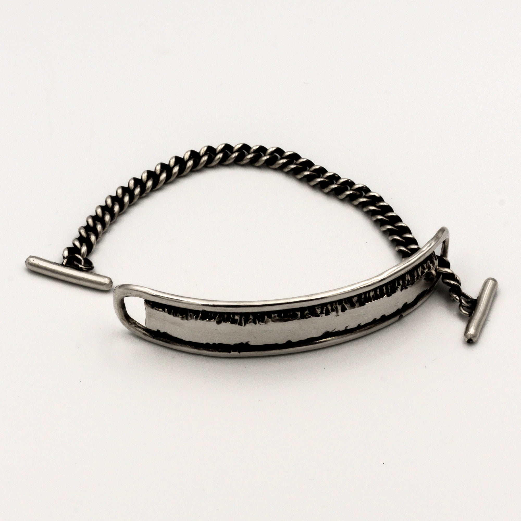 Silver bracelet with a textured band on a white background