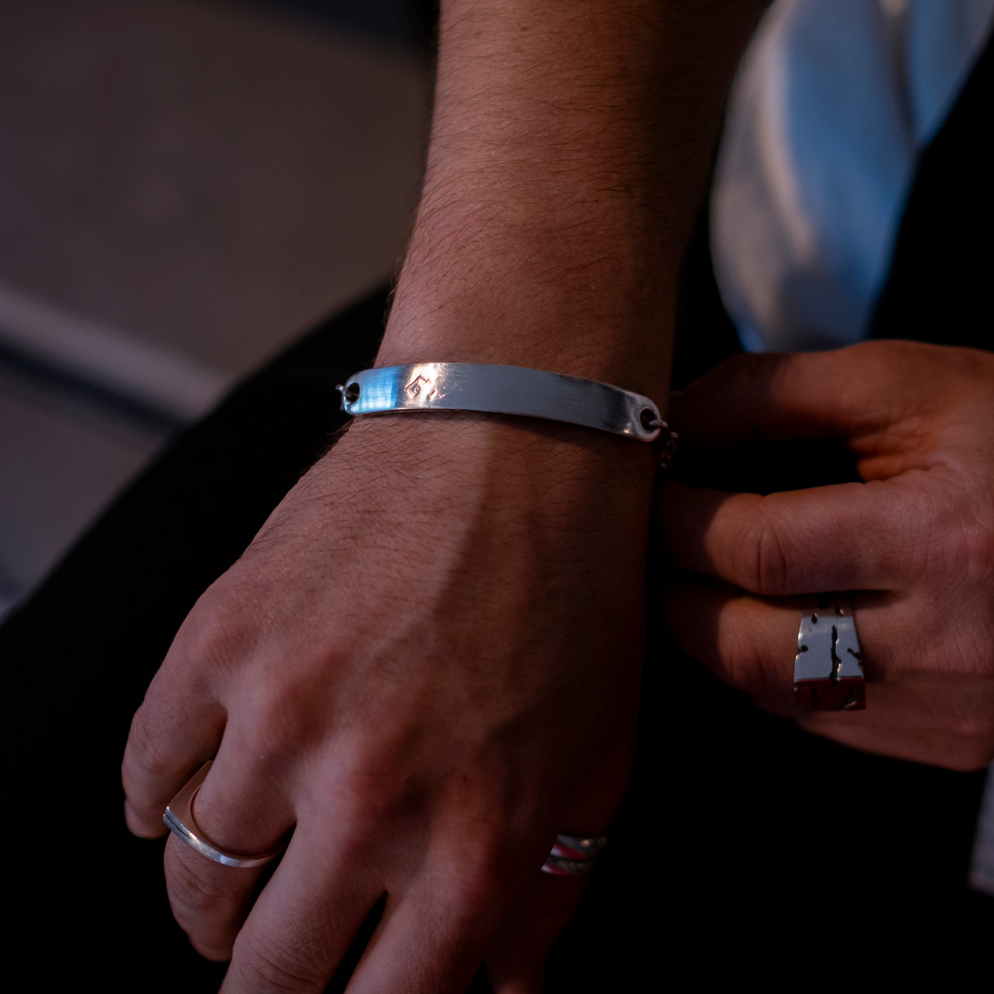 Close-up of a person's wrist wearing a silver bracelet with a blurred background