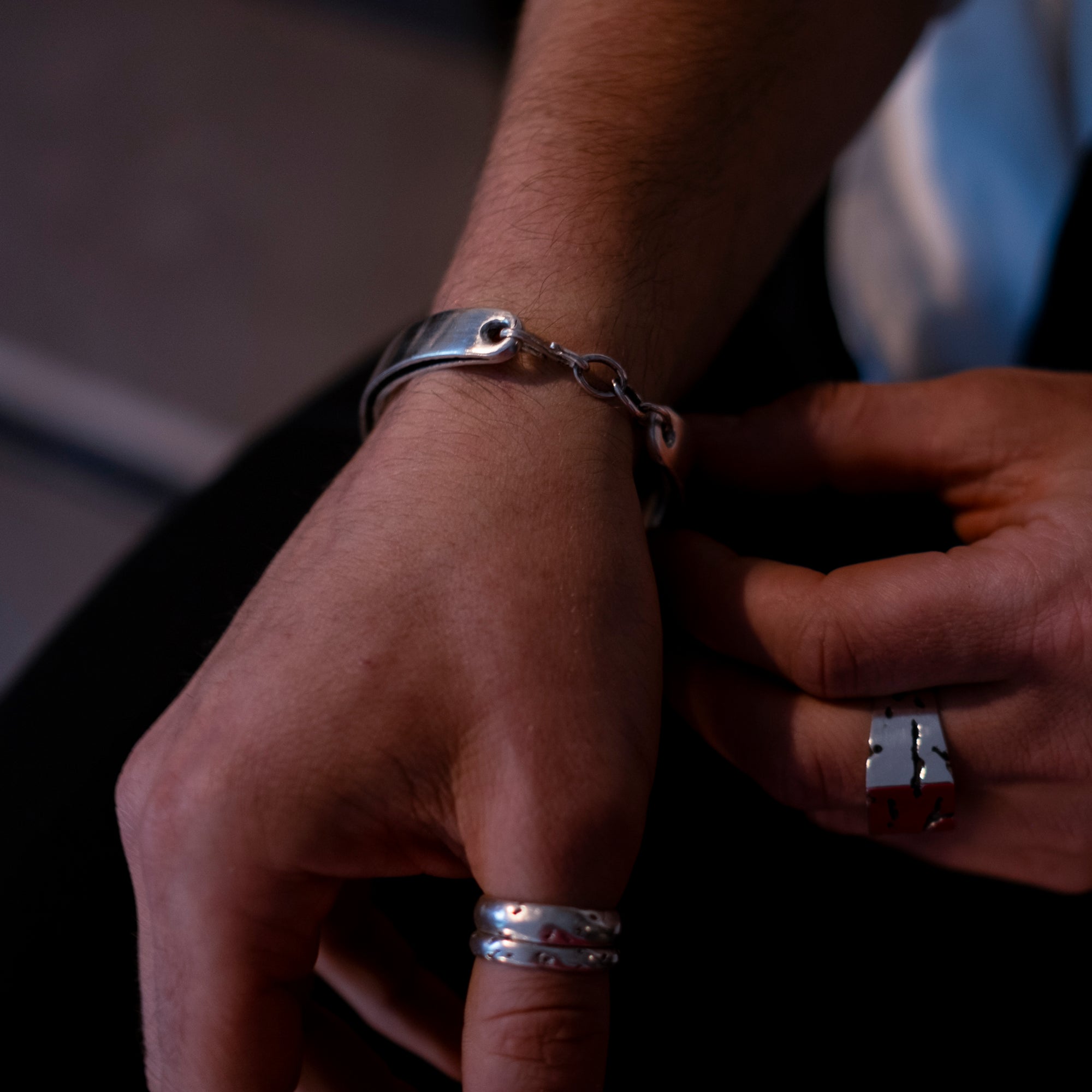 Close-up of a person's wrist with silver bracelet and rings.