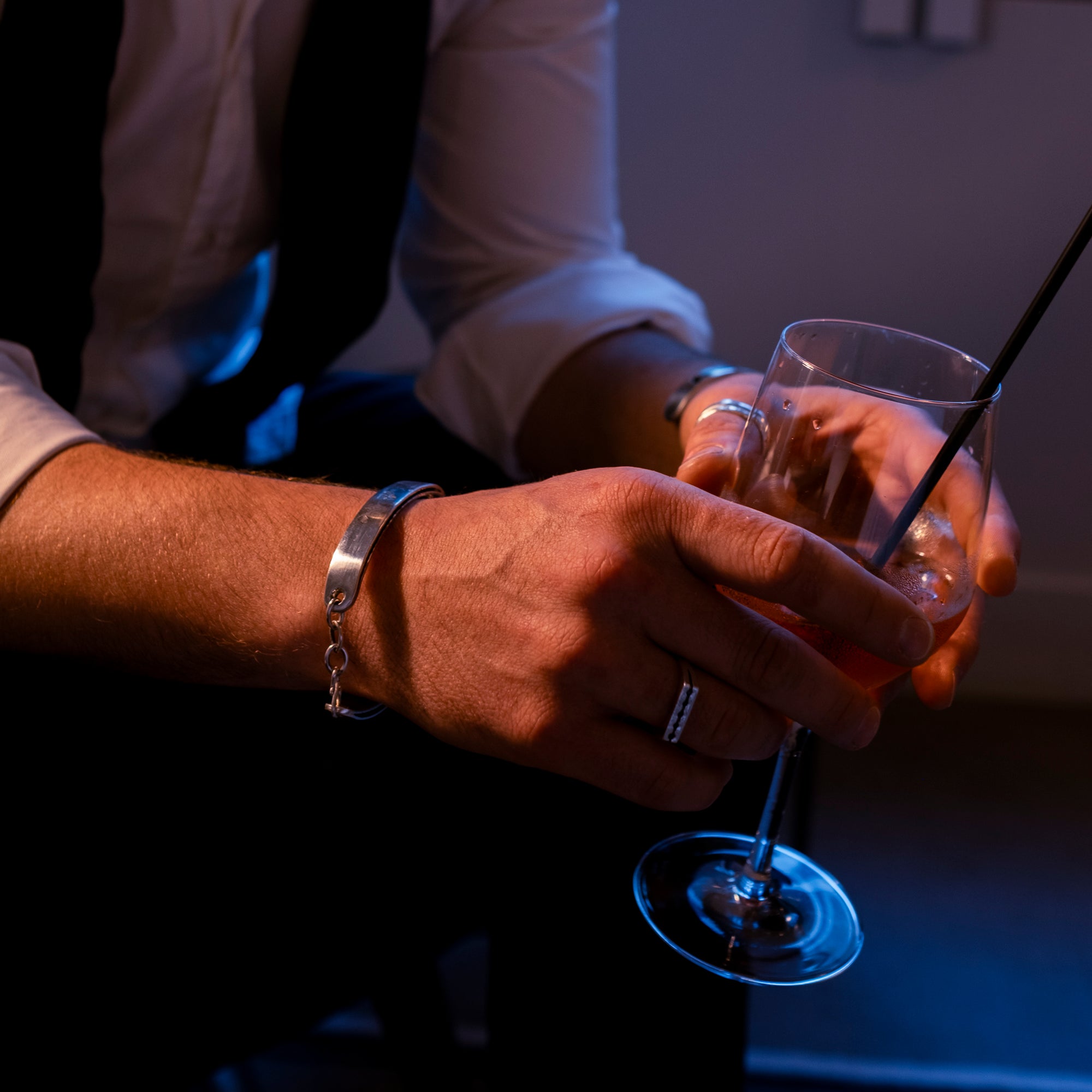 Person holding a cocktail glass with a silver bracelet