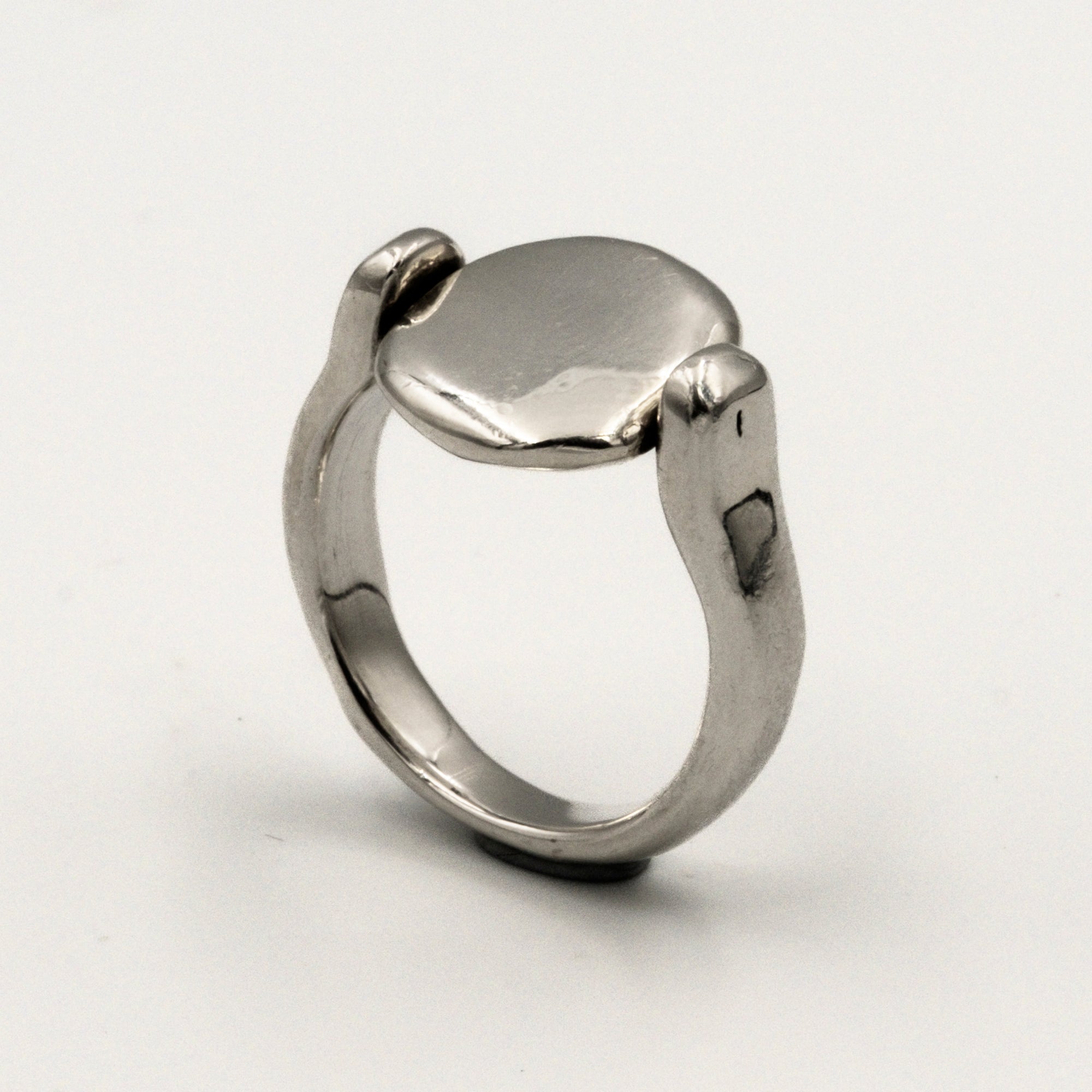 Silver ring with a smooth, oval-shaped tablet on a light gray background