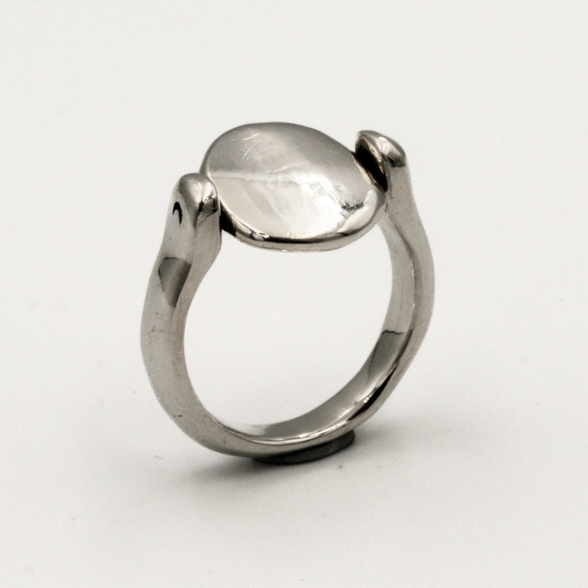 Silver ring with a smooth, oval-shaped tablet on a light gray background