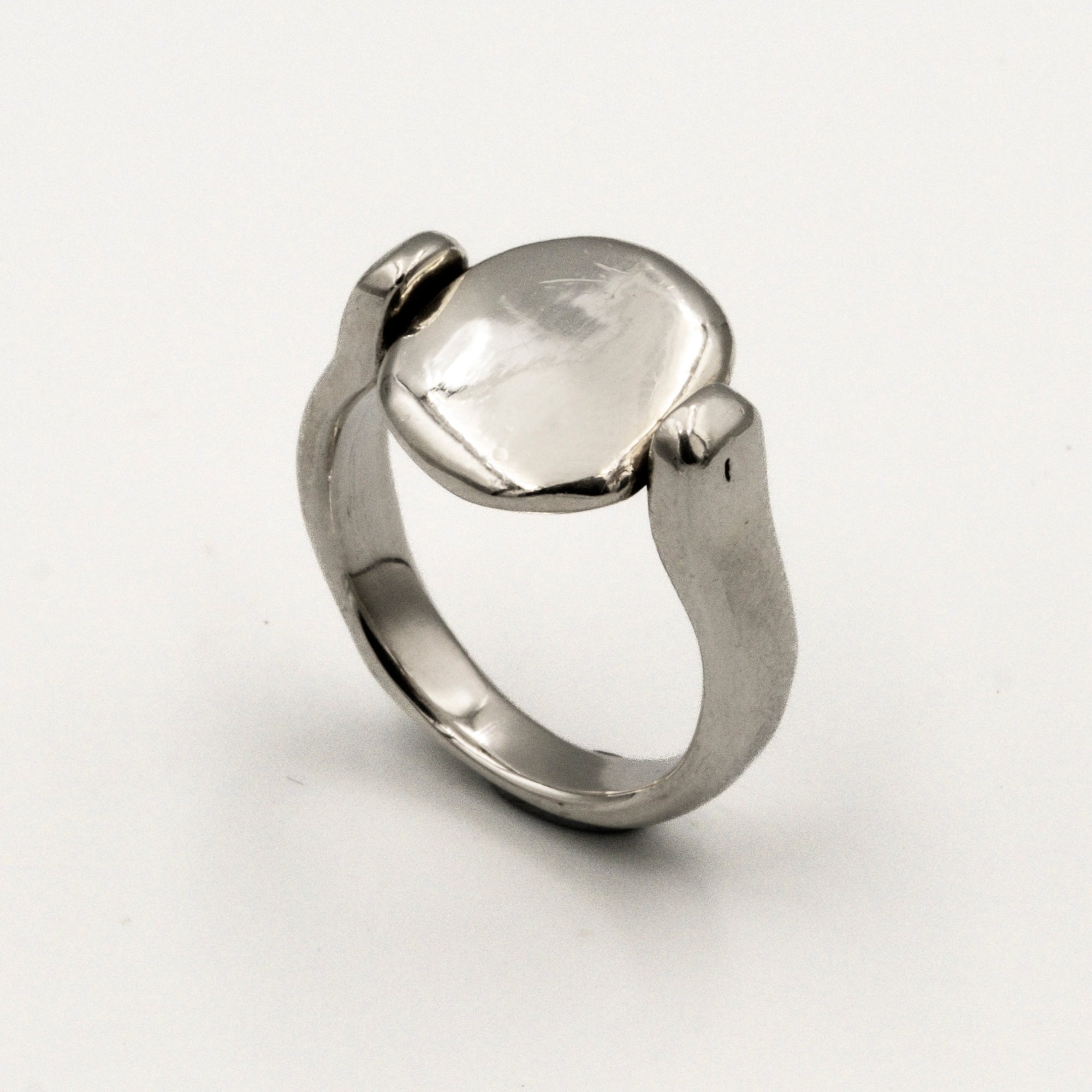 Silver ring with a smooth, oval-shaped tablet on a light gray background