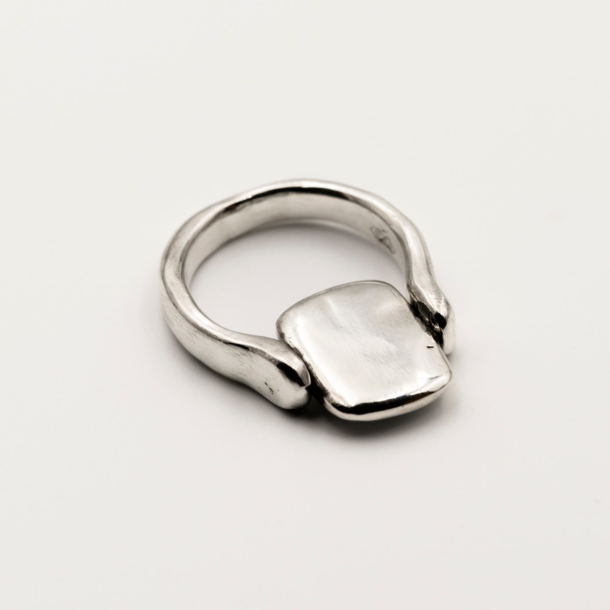 Silver ring with a rectangular tablet on a white background