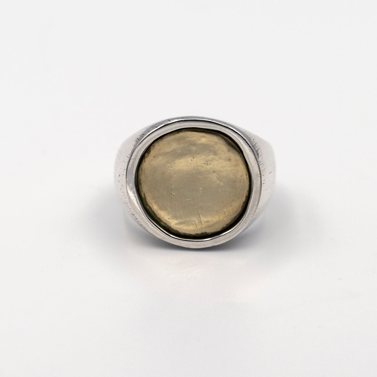 Silver ring with a gold coin inlay on a white background