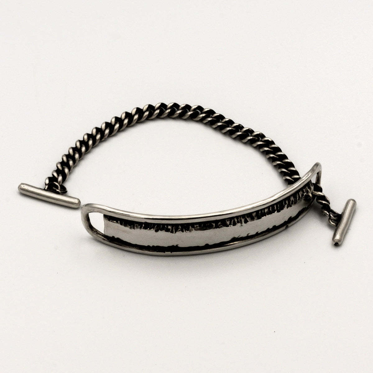 Silver bracelet with a textured band on a white background