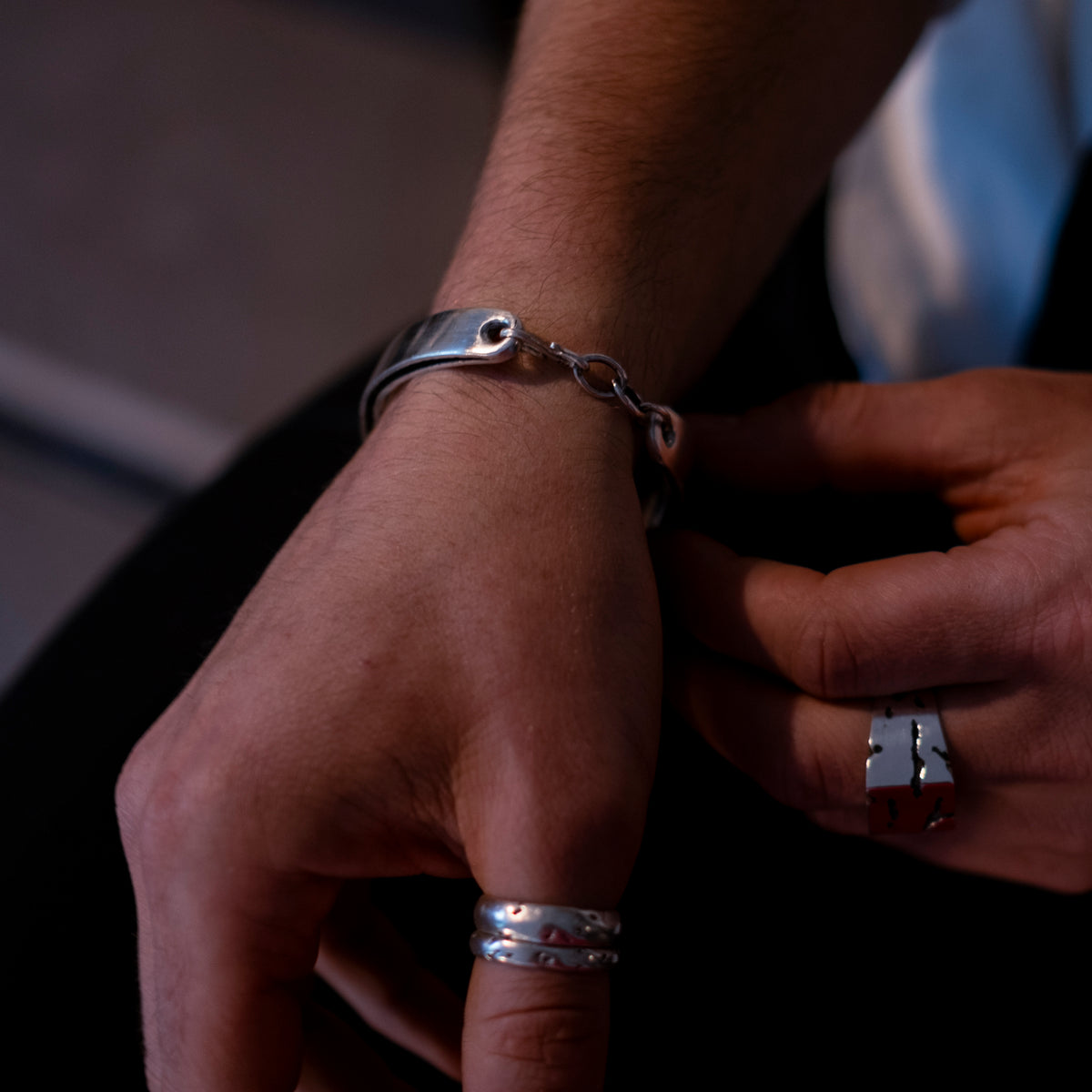 Close-up of a person's wrist with silver bracelet and rings.