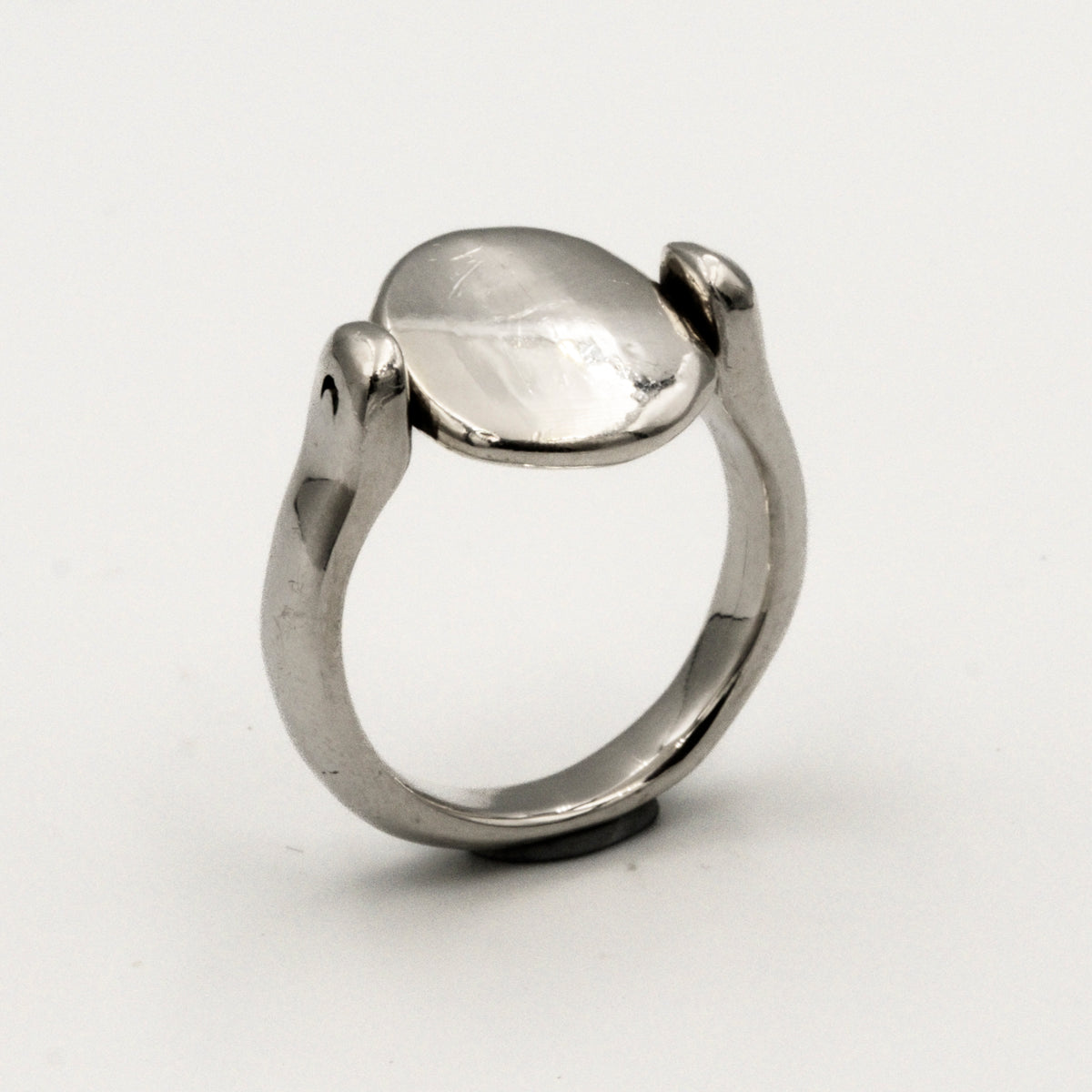 Silver ring with a smooth, oval-shaped tablet on a light gray background