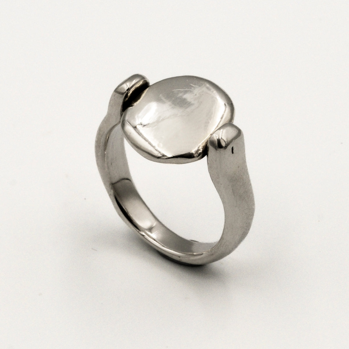 Silver ring with a smooth, oval-shaped tablet on a light gray background